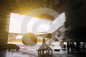 White passenger airliner under maintenance in the hangar. Repair of jet plane and checking mechanical systems for flight