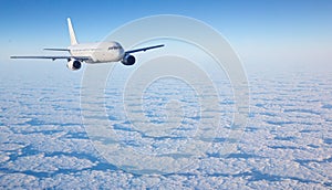 White passenger airplane flying above beautiful cloudscape on blue sky