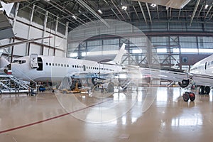 White passenger airplanes in the aviation hangar. Airliners under maintenance