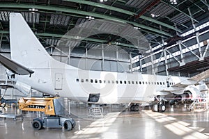 White passenger jetliner in the aviation hangar. Jet plane under maintenance
