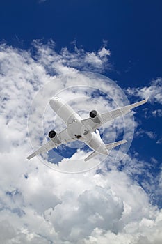 white passenger plane flies against backdrop of beautiful white clouds on blue sky