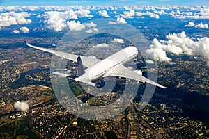 White passenger plane in flight. Aircraft flies above the big city.