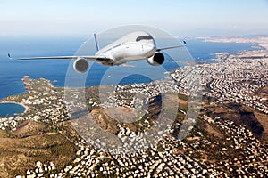 White passenger plane in flight. Aircraft flies above the big city. Front view