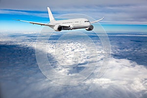 White passenger plane in flight. Aircraft fly above the clouds. Front view.