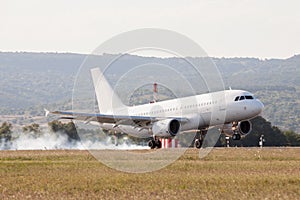 White passenger plane is landing on the airport. Touchdown with tire smoke