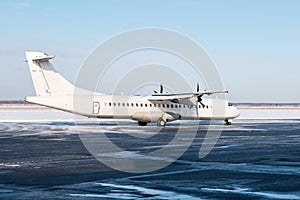 White passenger turboprop aircraft on the airport apron in cold winter weather