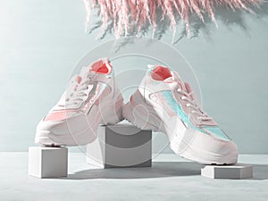 White pastel sneakers with sequins on geometric podiums with pampas