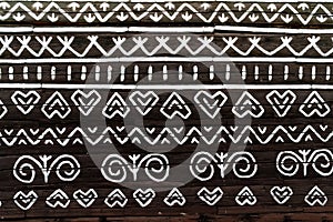 White pattern ornament painting on the dark wood wall in Slovakian old village Cicmany. European history heritage and black and