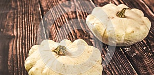 white pattypan squashed on dark wooden board, whole raw vegetable.