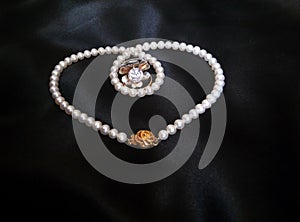 White pearl necklace with rings on black silky background
