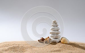 White pebble pyramid with small seashells on a light gray background