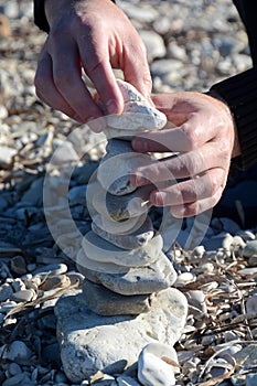 White pebble tower in progress by a man