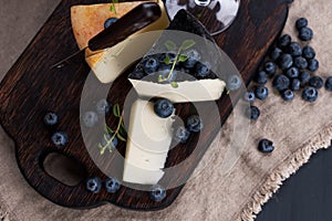 White pecorino cheese and blueberries. Traditional Italian hard cheese and a glass of red wine. Wooden background and dark style