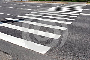 White pedestrian crosswalk across the road with asphalt pavement. Diagonal