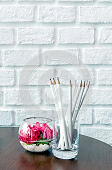 White pencils in a glass beside beautiful flower glass jar