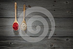 White pepper and goji berries on wooden spoons and wooden background