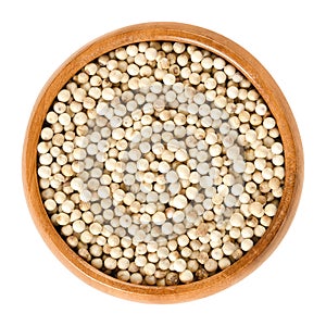 White pepper in wooden bowl over white