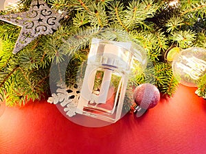 White perfume glass bottle, fir tree, stars, balls and magic lights on red background. Christmas gift, mock-up