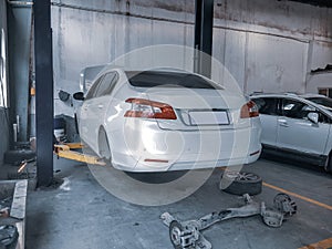 A white Peugeot 408 was lifted up by a lift in the workshop. All four wheels were removed for maintenance. photo
