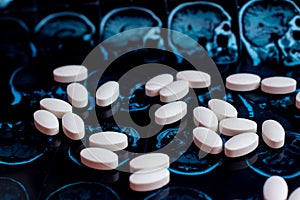 White pharmaceutical medicine pills on magnetic brain resonance scan mri background. Pharmacy theme, health care