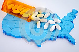 White pharmaceutical pills spilling from prescription bottle over map of America