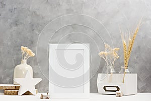 White Photo frame mock up with plants in vase with wooden and ceramic home decor on shelf. Scandinavian style