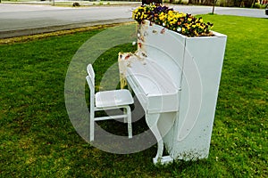 White piano and chairs with romantic decor in summer in garden. Decor for a wedding or a romantic dinner. Grand piano