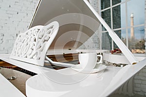 White piano with cup of tea in white room