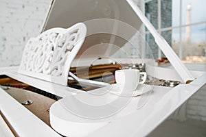 White piano with cup of tea in white room