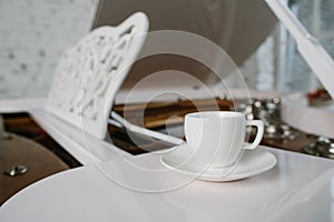 White piano with cup of tea in white room