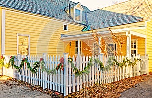 white picket fence strung with green garland and red bows for Christmas on street corner