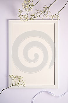 White picture frame with empty template, gypsophila flowers and fabric ribbon, mockup card