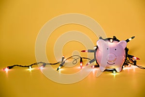 White piggy bank with Christmas string lights on happy December festival, Enjoy savings for spending money on the holiday`s