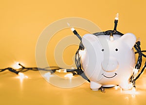 White piggy bank with Christmas string lights on happy December festival, Enjoy savings for spending money on the holiday`s