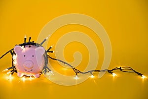 White piggy bank with Christmas string lights on happy December festival, Enjoy savings for spending money on the holiday`s