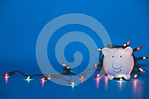 White piggy bank with Christmas string lights on happy December festival, Enjoy savings for spending money on the holiday`s