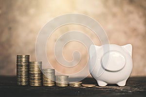 White piggy bank and coin on wood