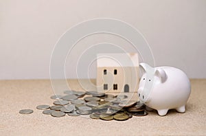 white piggy bank Coins and houses on a wooden table, for saving money wealth, and financial concepts, save home loan.