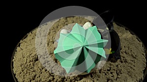 A white piggy bank stands on a sandy beach and revolves on a black background.