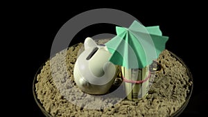 A white piggy bank stands on a sandy beach and spins on a black background.