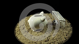 A white piggy bank stands on a sandy beach and spins on a black background.
