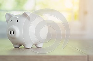 A white piggy bank was placed on the wooden table in the office in the morning