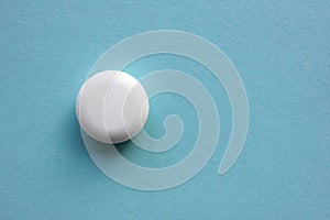 White pill on blue background. View from above of big round tablet. Copy space