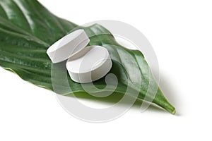 White pill lying on a green leaf