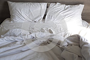 White pillow and blanket on bed unmade. Messy bed after used . wrinkled white bed, pillow and bedsheets
