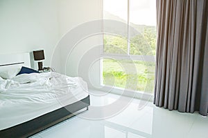 White Pillow, White Blanket And White Towel On Bed In Bedroom With Soft Lighting In Morning