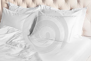 White pillows, duvet and duvet case on bed with beige headboard