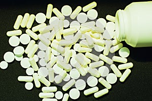 White pills on a black background. The concept of health, pharmaceuticals and treatment