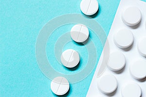 White pills and blister on a blue background. Medications. Close up, macro.