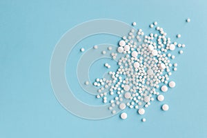 White pills on a blue background. Capsules and round pills close-up.